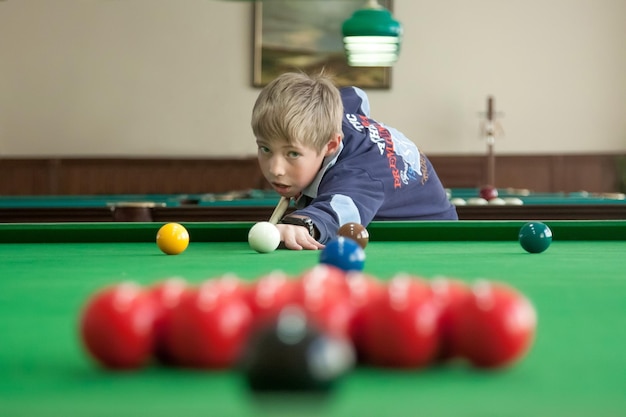 Tiener speelt snooker Rode ballen staan op de voorgrond