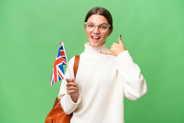 Tiener student blank meisje met een vlag van het Verenigd Koninkrijk over geïsoleerde achtergrond telefoongebaar maken Bel me terug teken