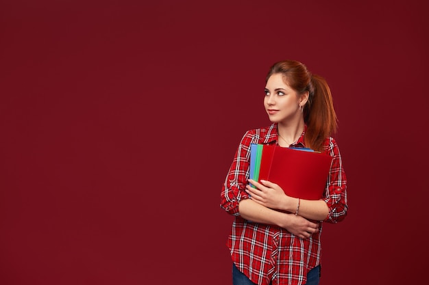 Tiener student meisje op een rode muur met mappen