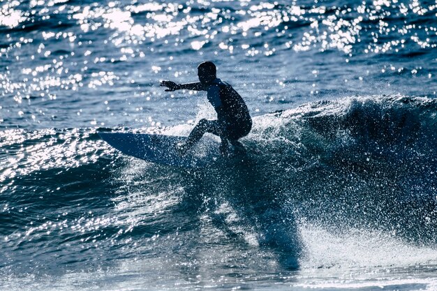 Tiener surfen op de golf in tenerife playa de las americas - witte en zwarte wetsuits en mooie en kleine golf