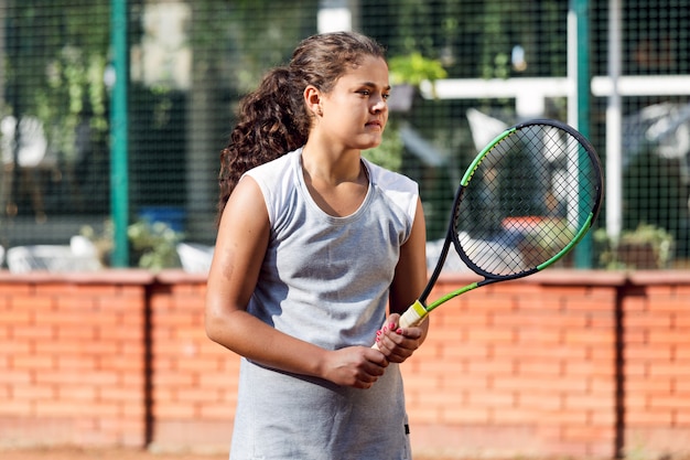 Tiener tennis speler meisje opleiding hof meisje racket bal brunette lang haar zon portret leren groene zomer groen