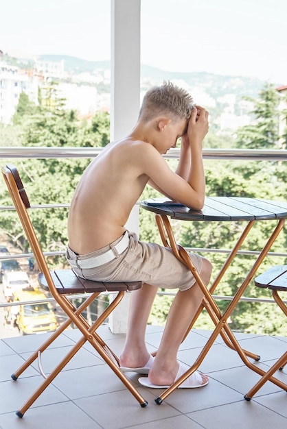 Tiener topless leest ebook ondergedompeld in plot zittend op het balkon van het hotel tijdens de zomervakantie