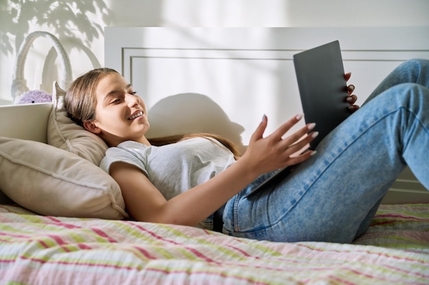 Tiener vrouw liggend op de bank thuis met behulp van laptop voor conferentie-chat video-oproep