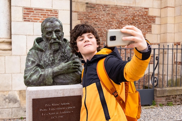 Tienerjongen die een selfie maakt met een monument en grappige inhoud maakt voor sociale media Reizende student sightseeing