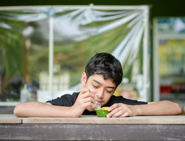 Foto tienerjongen die vruchtensap drinkt in het park dat zomertijd kampeert