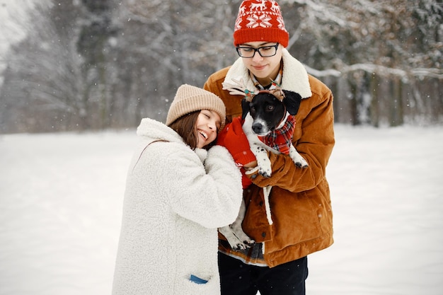 Tienerjongen en -meisje met hun schattige zwarte hond die in het winterpark staan