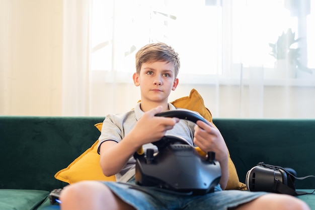 Tienerjongen gamer die racegames speelt op de computer Hij gebruikt het stuur Zich klaarmaken voor professioneel rijden Stimulatie rijdend kind dat videogame speelt