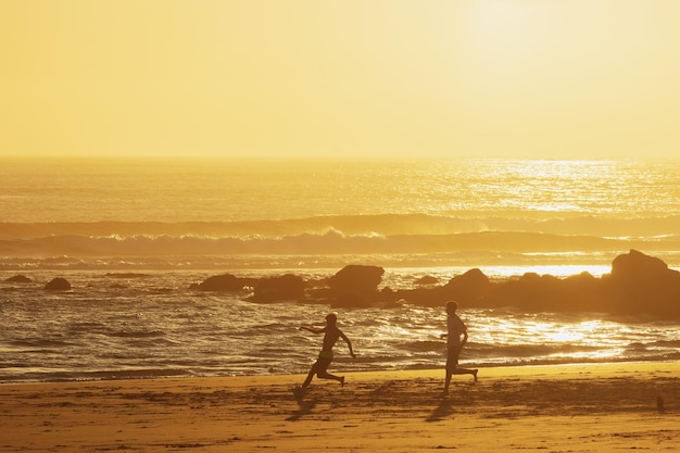 Tienerjongens spelen een bal op het strand bij zonsondergang