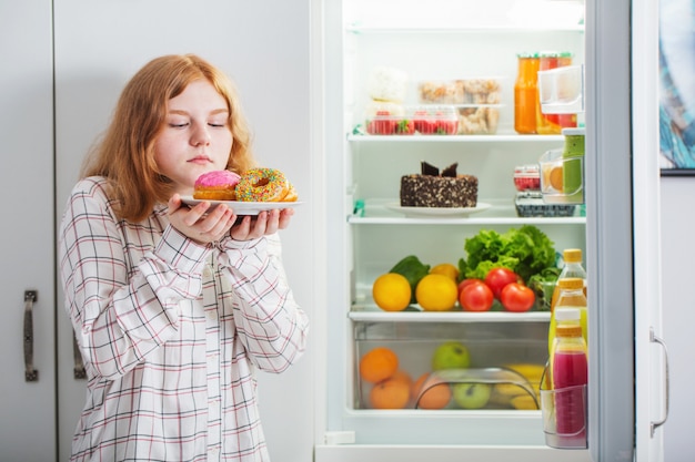 Tienermeisje bij koelkast met voedsel