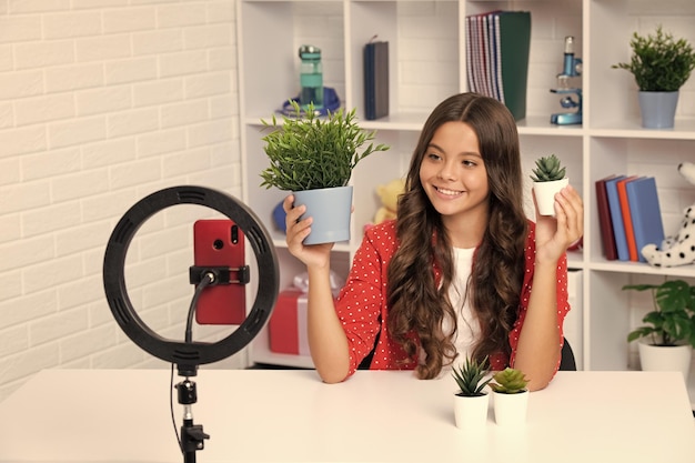 Foto tienermeisje blogger influencer gebruikt selfie led-lamp en smartphone op statief voor het maken van online video-tutorial tienervlogger maakt vlog voor kinderkanaal gelukkig lachend meisje