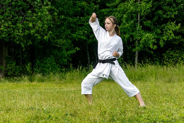 Tienermeisje dat buiten karate kata beoefent, voert de age-uk uit (stijgend of opwaarts blok)