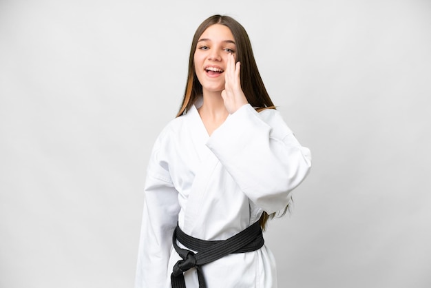 Tienermeisje dat karate doet over geïsoleerde witte achtergrond schreeuwend met wijd open mond