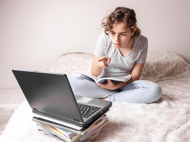 Tienermeisje dat thuis online studeert. schoolmeisje met lap top op het bed. thuisonderwijs