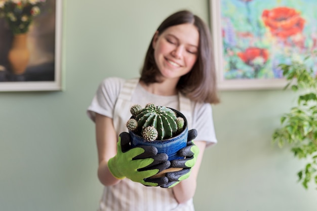 Tienermeisje die cactus in pot houdt. Hobby's en vrije tijd, tuinieren, kamerplant, potvriendenconcept