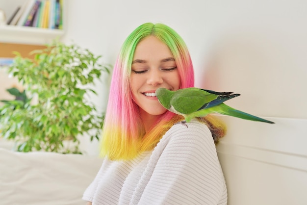 Tienermeisje die een papegaai kust Close-upgezicht van mooie jonge vrouw en groene quakerpapegaai liefde van de eigenaar en huisdierenvogel