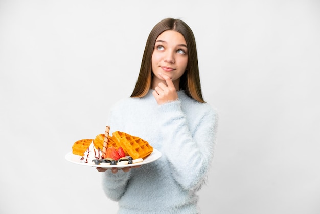 Tienermeisje die wafels over geïsoleerde witte achtergrond houden en omhoog kijken