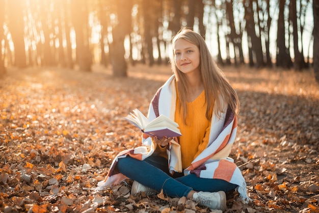 Tienermeisje doet haar favoriete hobby en leest een boek in het park, allemaal in felgele en oranje kleuren