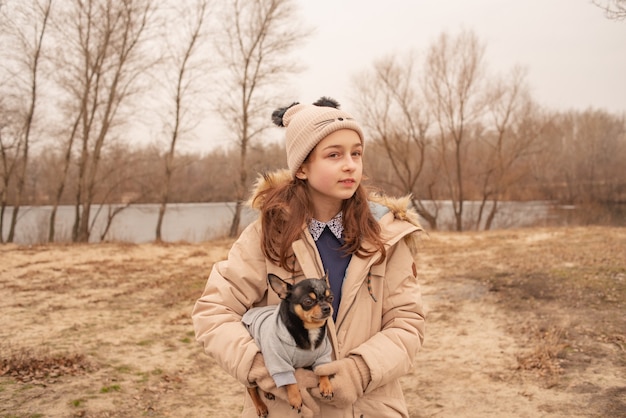 Tienermeisje en chihuahuahond. Schoolmeisje en haar huisdier in het park in de natuur. Liefde voor dieren.