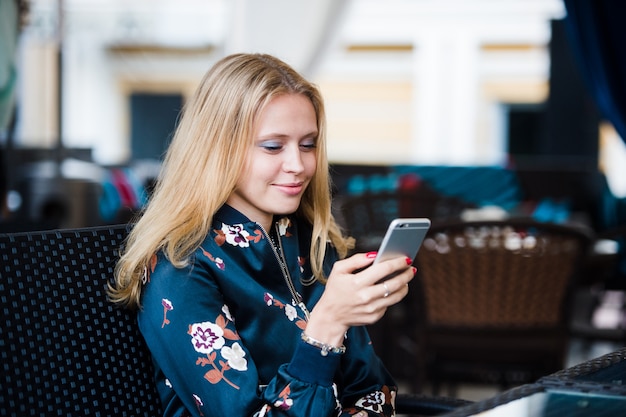 Tienermeisje gebruikend een slimme telefoon en texting zitting op bank van een stedelijk park