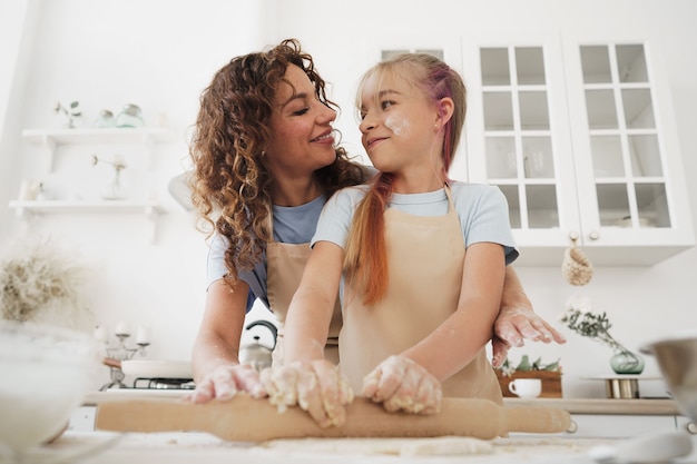 Tienermeisje helpt haar moeder om deeg in hun keuken thuis te koken