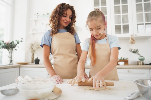 Tienermeisje helpt haar moeder thuis deeg te koken in hun keuken