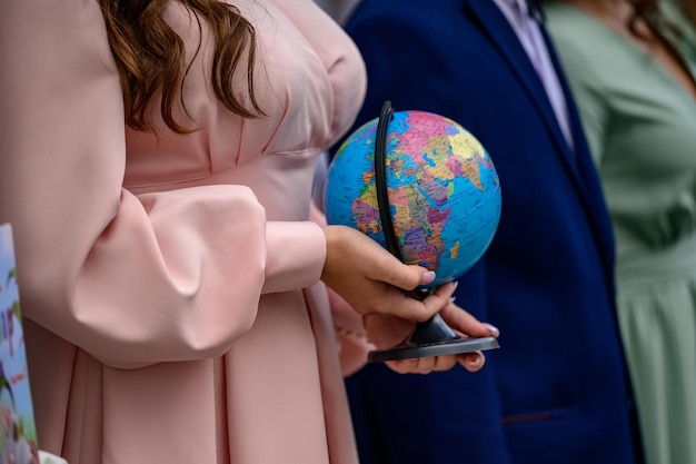 Foto tienermeisje houdt een kleine wereldbol een kopie van de aarde in de handen van een kind
