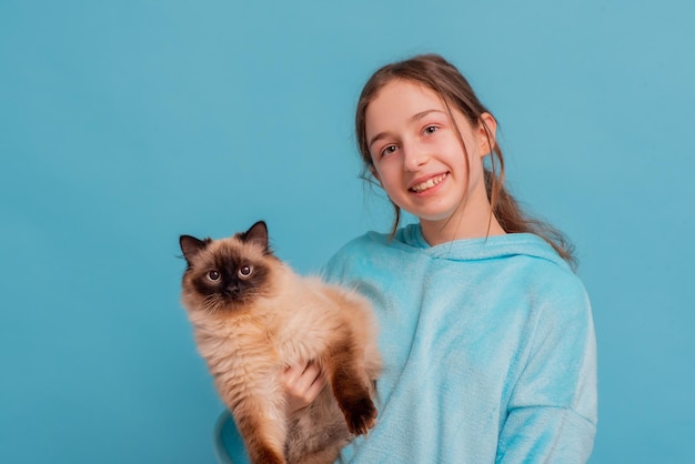 Tienermeisje in een blauwe hoodie houdt een kat in haar armen Meisje en huisdier