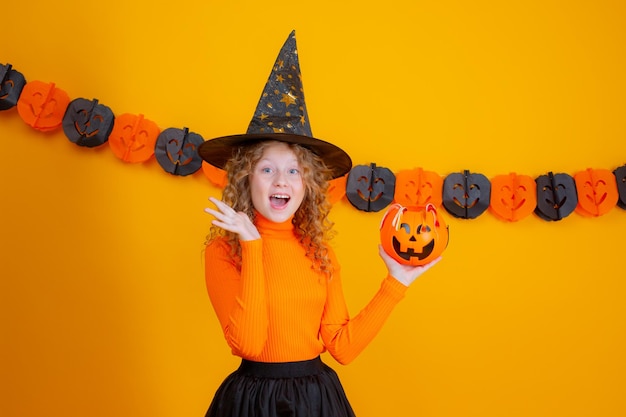Tienermeisje in een heksenkostuum op een gele achtergrond halloween