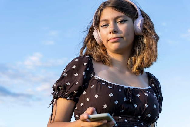 Tienermeisje in een jurk luistert naar muziek op haar smartphone