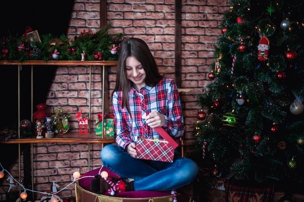 Tienermeisje in een plaid shirt opent vak kerstcadeau