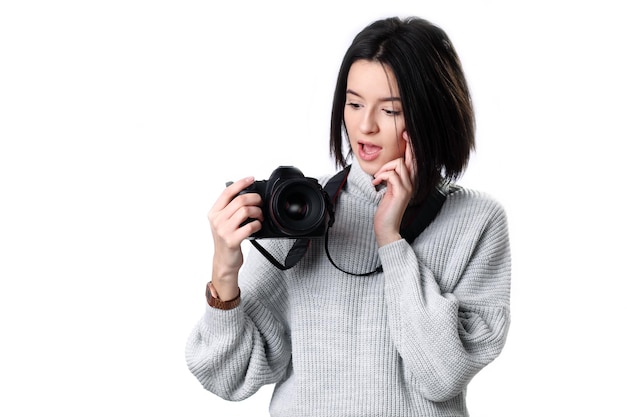 Tienermeisje in het kijken naar de fotocamera in haar handen met nieuwsgierige en verbaasde uitdrukking