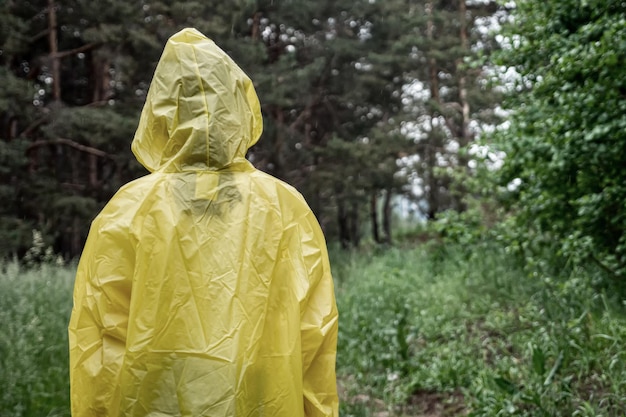 Tienermeisje in regenkleding staat op weg in regenachtig bos