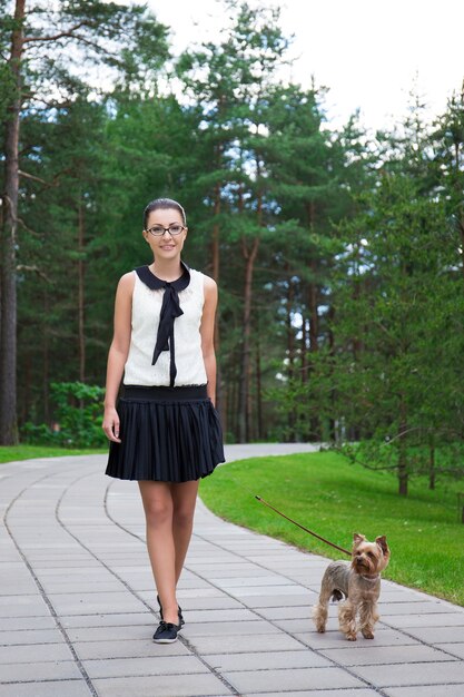 Tienermeisje in schooluniform wandelen met hond yorkshire terrier in zomer park