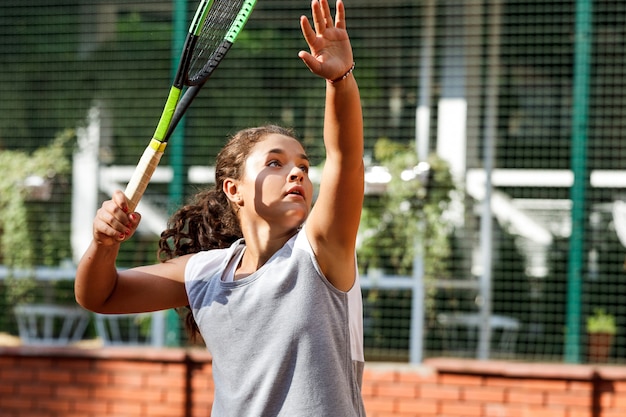 Tienermeisje in sportieve outfit tennissen