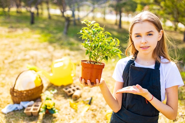 Tienermeisje in zwarte schort tuinieren in de achtertuin tuin