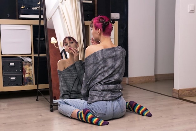 Tienermeisje kijkt in de spiegel in de studio en onderzoekt zorgvuldig haar gezicht