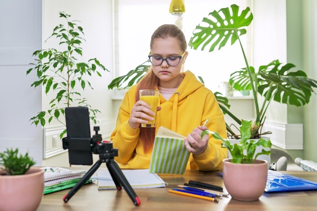 Tienermeisje kijkt naar de webcam met een smartphone voor een online les