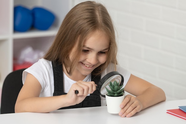 Tienermeisje kijkt naar plant door vergrootglas terug naar school studie biologie onderzoek onderwijs