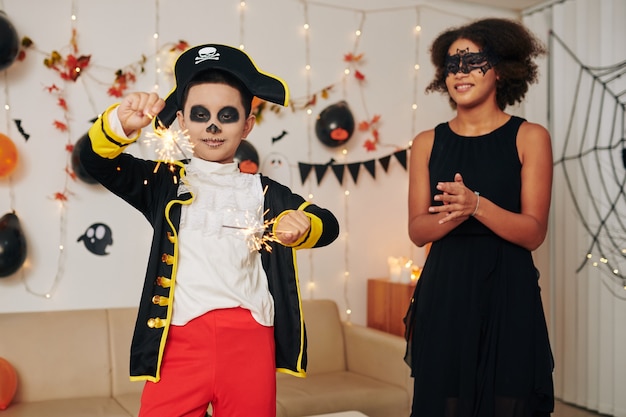 Tienermeisje klapt voor jongere broer in piratenkostuum die Bengaalse lichten verbrandt op Halloween-feest