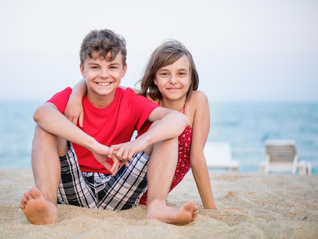 Foto tienermeisje knuffelt jongen voor altijd samen portret van gelukkige broer en zus die overdag op het strand spelen grappig stel kinderen lachen met een perfecte glimlach