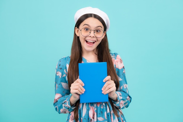 Tienermeisje leerling houdt boeken notitieboekjes geïsoleerd op blauwe achtergrond kopie ruimte Terug naar school tiener levensstijl onderwijs en kennis Opgewonden tiener verbaasd en vrolijke emoties