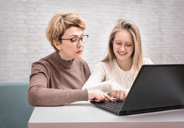 Tienermeisje leert moeder op de computer te werken.