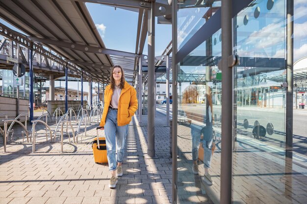 Foto tienermeisje loopt met een koffer op straat in de stad