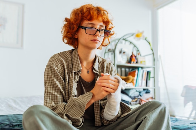 Tienermeisje met gebroken arm met rood haar in de slaapkamer