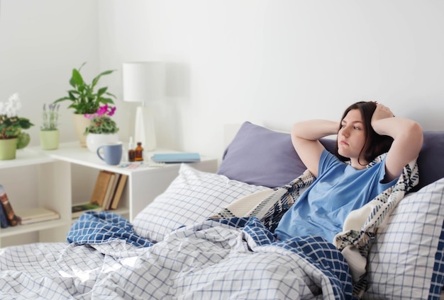 Tienermeisje met hoofdpijn op bed in witte kamer