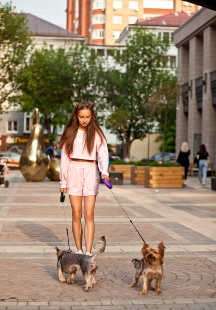 Tienermeisje met kleine honden die buiten in een park lopen