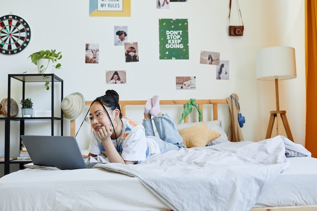 Tienermeisje met laptop op bed