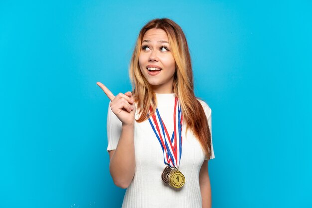 Tienermeisje met medailles over geïsoleerde achtergrond die de oplossing wil realiseren terwijl ze een vinger opheft