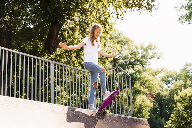 Foto tienermeisje met pennyboard klaar om naar beneden te gaan op de speeltuin van het skateboardpark sportuitrusting extreme lifestyle