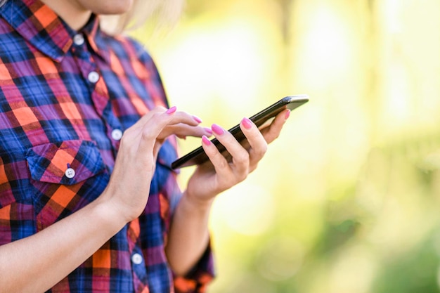 Tienermeisje met roze nagels tikt op haar mobiele telefoon